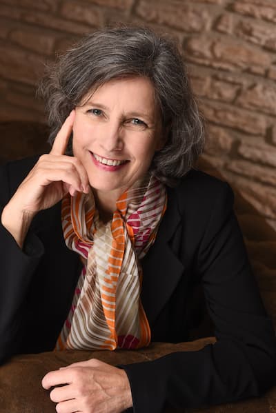 Indoor headshot of Christina Winkler smiling with her hand against the side of her face, illustrating that Christina Winkler gives people space to make meaningful and lasting improvements in their lives.
