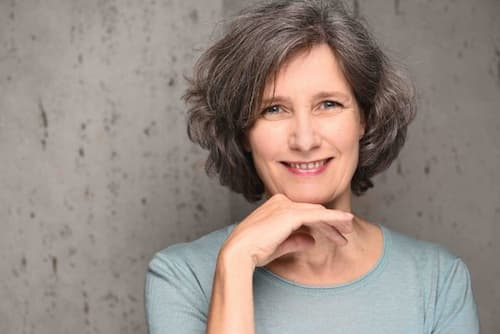 Indoor headshot of Christina Winkler smiling, with her hand under her chin. Christina Winkler offers therapy services both in-person in Nice and online.